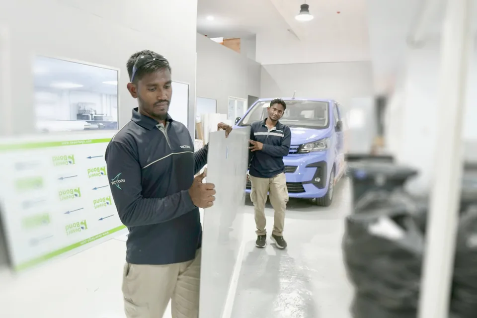 Victory team handling a sign panel in the workshop, with a branded van behind